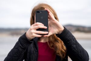 Una donna filma con uno smartphone, che tiene davanti al volto