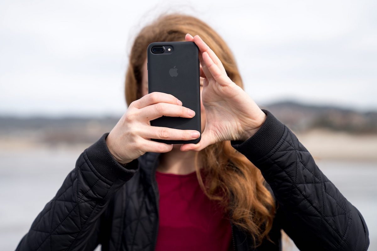 Frau mit Smartphone vor Gesicht am Fotografieren