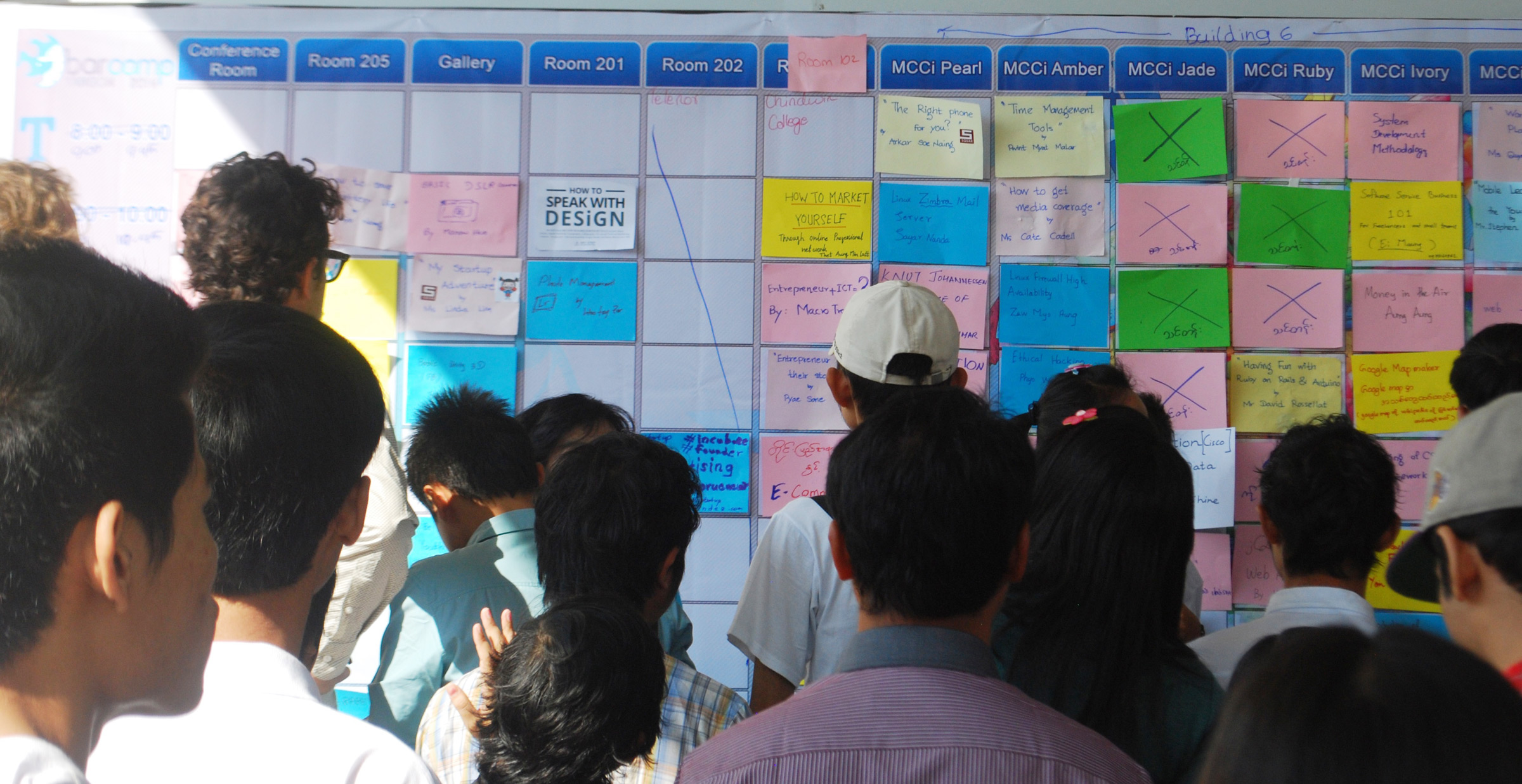 Viele Menschen vor einer Pinnwand bei der Sessionplanung eines Barcamps